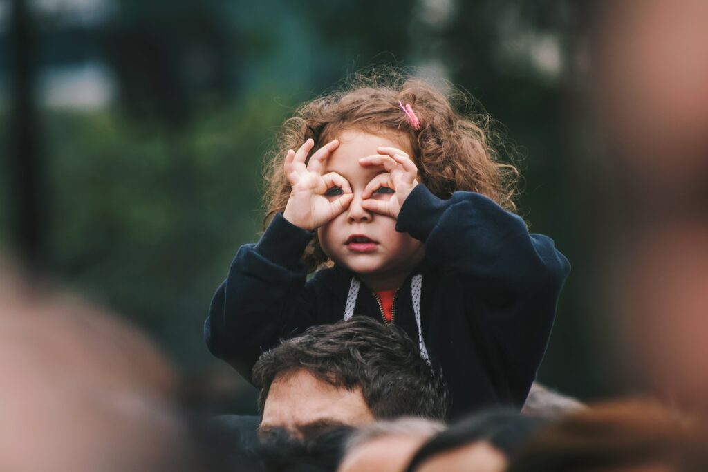 une petite fille qui fait des lunettes avec ses doigts